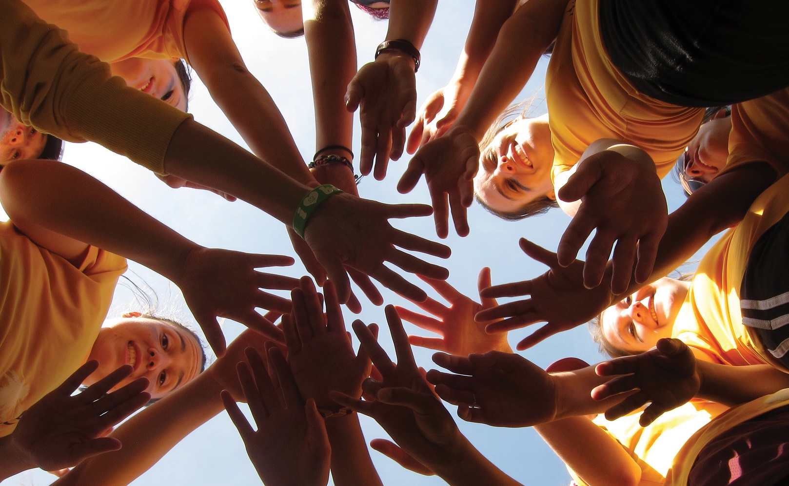 ASU students standing in a circle and placing their hands in the middle