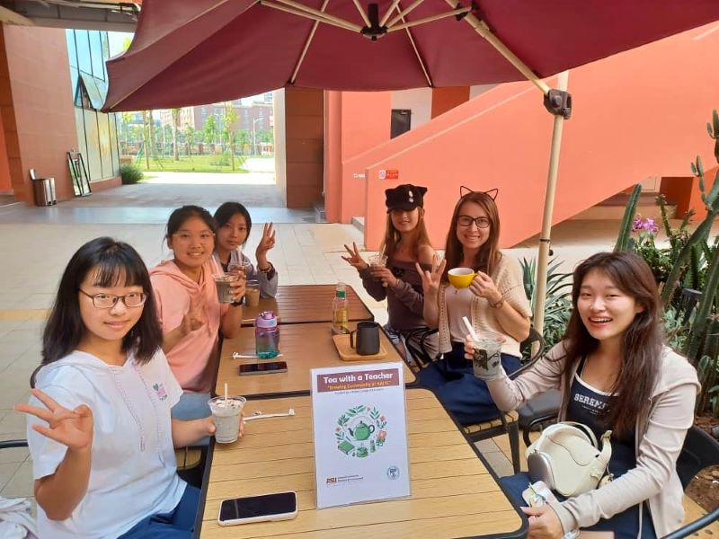 teacher and students enjoying conversation and coffee at an outside cafe