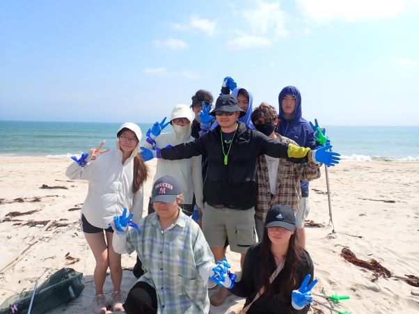 HAIC students grouped together in front of ocean after beach cleanup