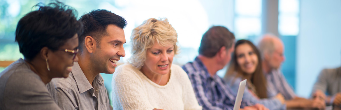 Adults talking and smiling while looking at a computer