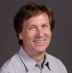 Eric Welch headshot - fair-skinned man, smiling, brown hair, gray collared shirt