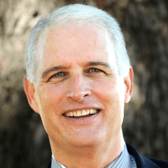 Robert Ashcraft headshot - fair-skinned man, smiling, white hair, blue-and-white-striped collared shirt, navy blazer